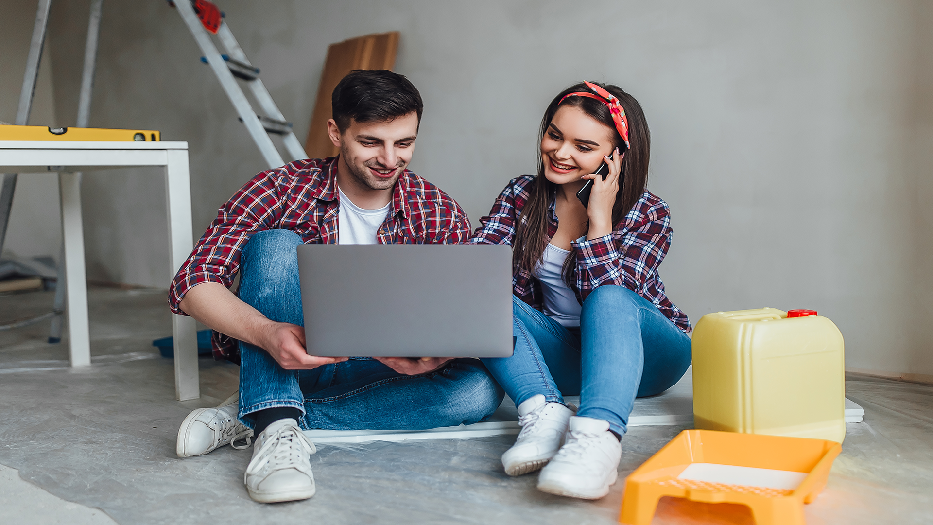 young-smiling-couple-renovating-remodeling-their-new-apartment-man-is-painting-walls-with-roller-woman-is-connecting-with-laptop